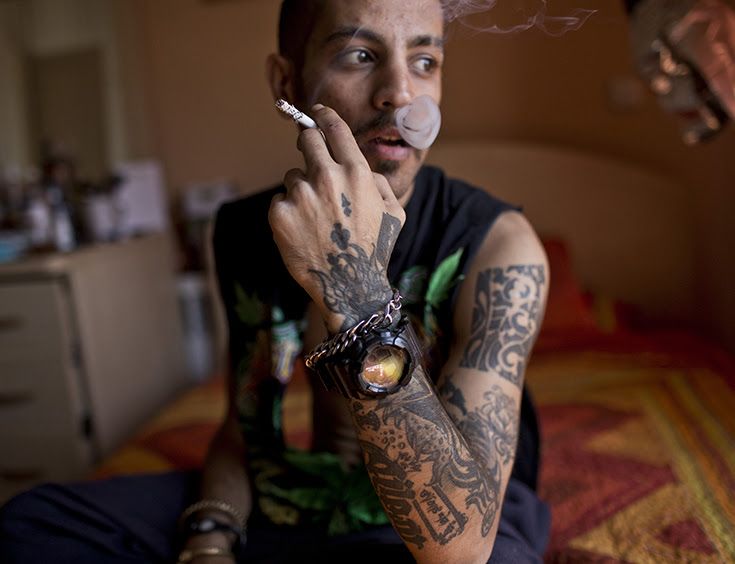 Siavash is smoking cigarette in his room. He is a tattooist. He got himself a hand tattoo.