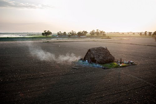 Bart De Bock - A man is showering outside his house in the middle of a field in Mandalay. His house is near U Bein Bridge, a very popular tourist attraction and can be seen from the bridge. He has no problem showering in front of thousands of tourists.